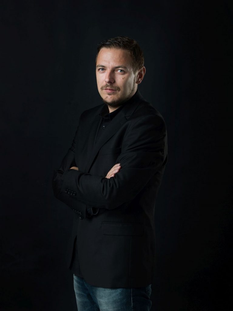 Low-key portret muškarca u crnom sakou na crnoj pozadini