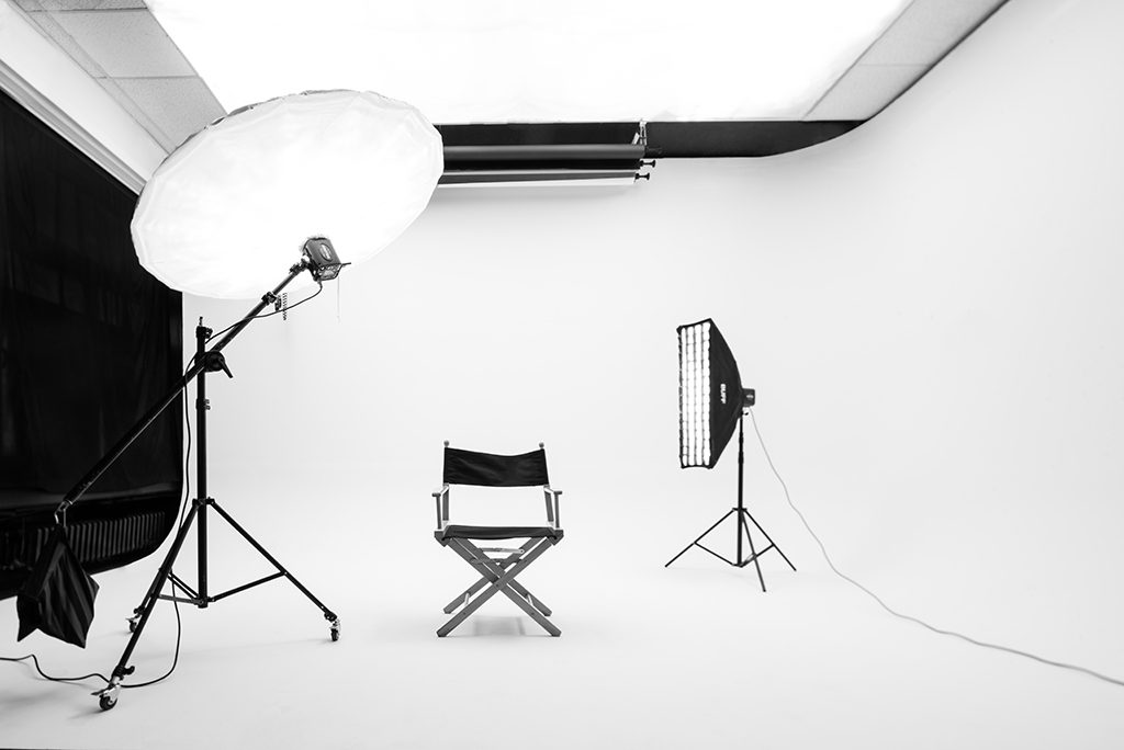 Bijela ciklorama izbliza: parabolični kišobran, strip softbox, rolne pozadina i rediteljska stolica
